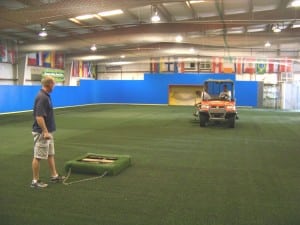 installers sweeping indoor artificial turf field
