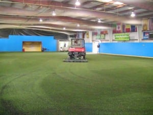 indoor artificial turf field being groomed by truck