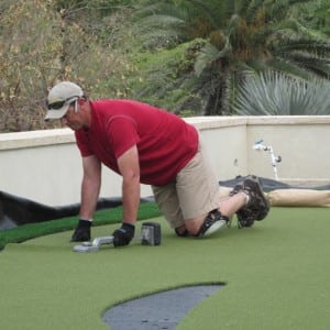 installer presses artificial turf seam for rooftop putting green