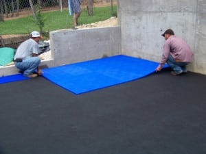 two men laying sport court tiles in backyard basketball installation