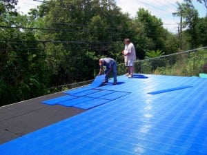 two men laying sport court tiles in backyard basketball installation