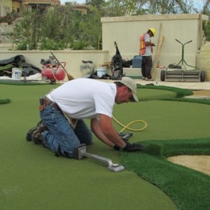 team installs fringe on the edge of artificial turf for putting green installation