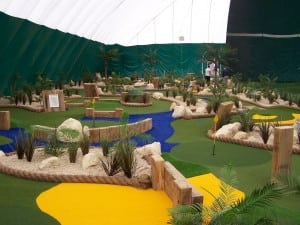 mini golf course with blue and yellow putting green turf inside sports dome