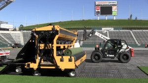 industrial spooling machine rolls up artificial turf from field