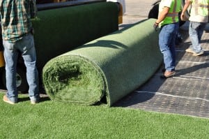 installers rolling up synthetic turf