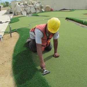installer rolling over turf around fringe for rooftop putting installation