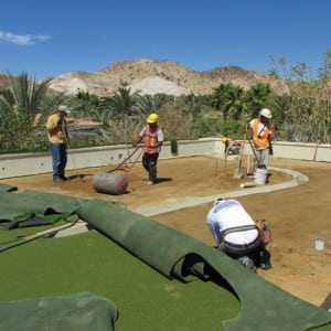 team rolling out turf and leveling dirt for putting green installation