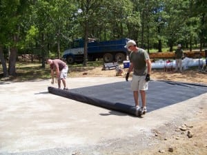 installers rolling out geotextile fabric for putting green installation