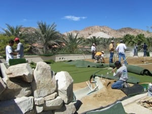 group of installers water dirt and unroll artificial turf for rooftop putting green installation