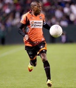 soccer player runs toward ball in the air