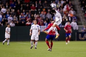 soccer player jumps into the air to head but soccer ball
