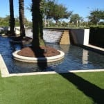 completed artificial lawn turf installation near water feature and palm trees