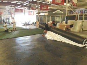 team unrolls large roll of turf ultrabasesystems base panels for indoor soccer installation