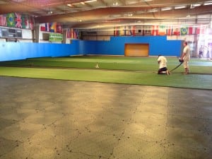 installers trim turf on top of base panels for indoor soccer field