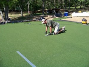 installer smoothing out artificial turf during putting green installation