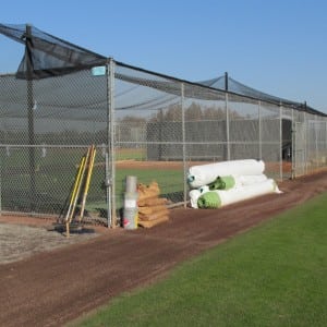 rolls of artificial turf rolled up and stacked near fence and installation equipment