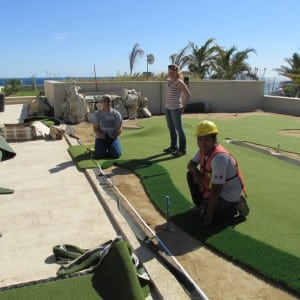 installers applying fringe to rooftop putting green