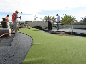 installers laying putting green turf on rooftop installation