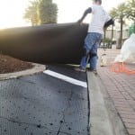 installer unrolling turf onto ultrabasesystems panels for artificial lawn turf installation
